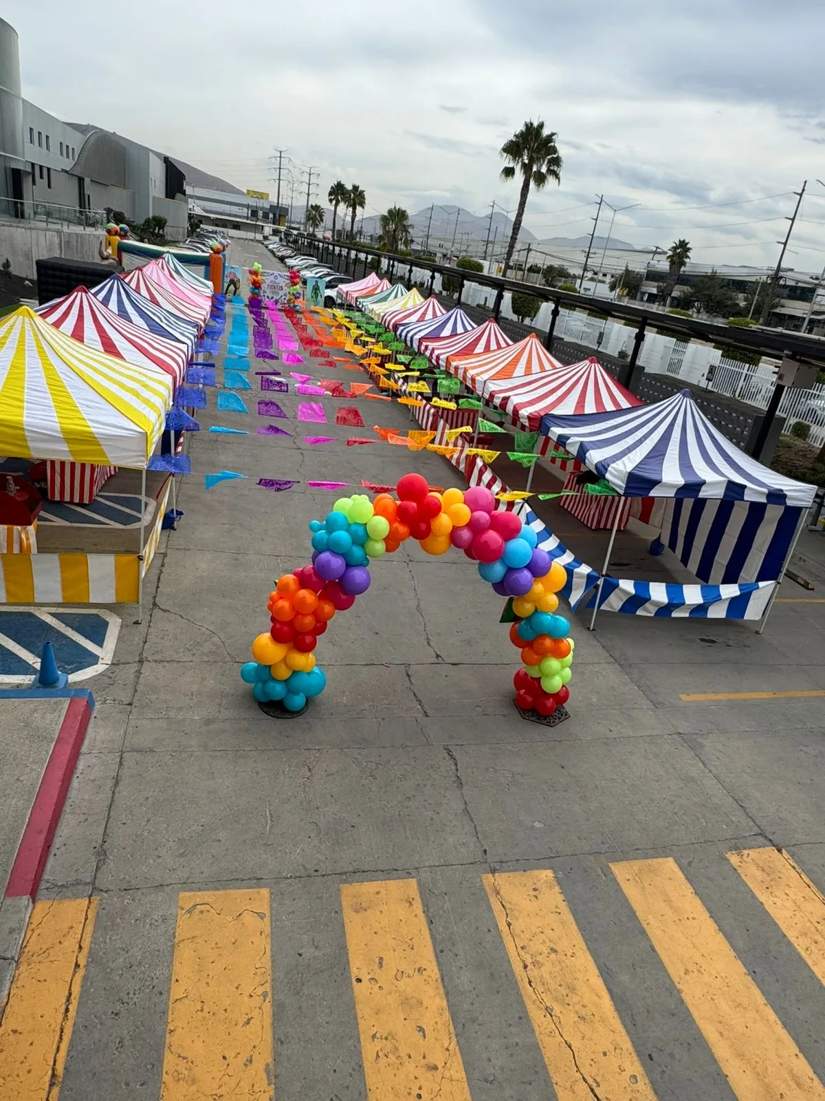 A row of red-and-white striped carnival booths set up in a grassy field with game signage and prizes hanging from the front counters in Fallbrook, CA