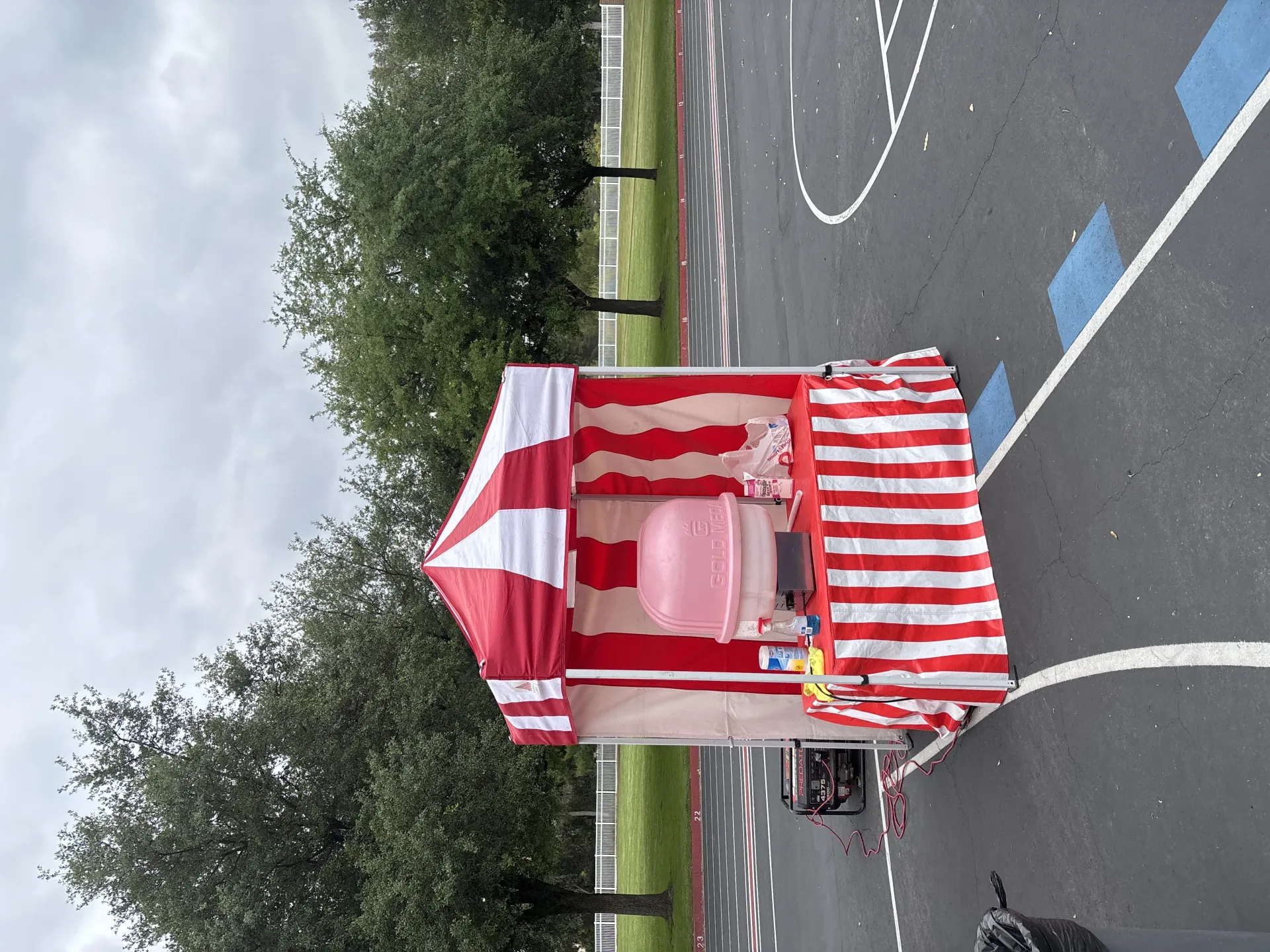 Children playing a ring toss game at a striped carnival booth while an attendant hands out a small prize