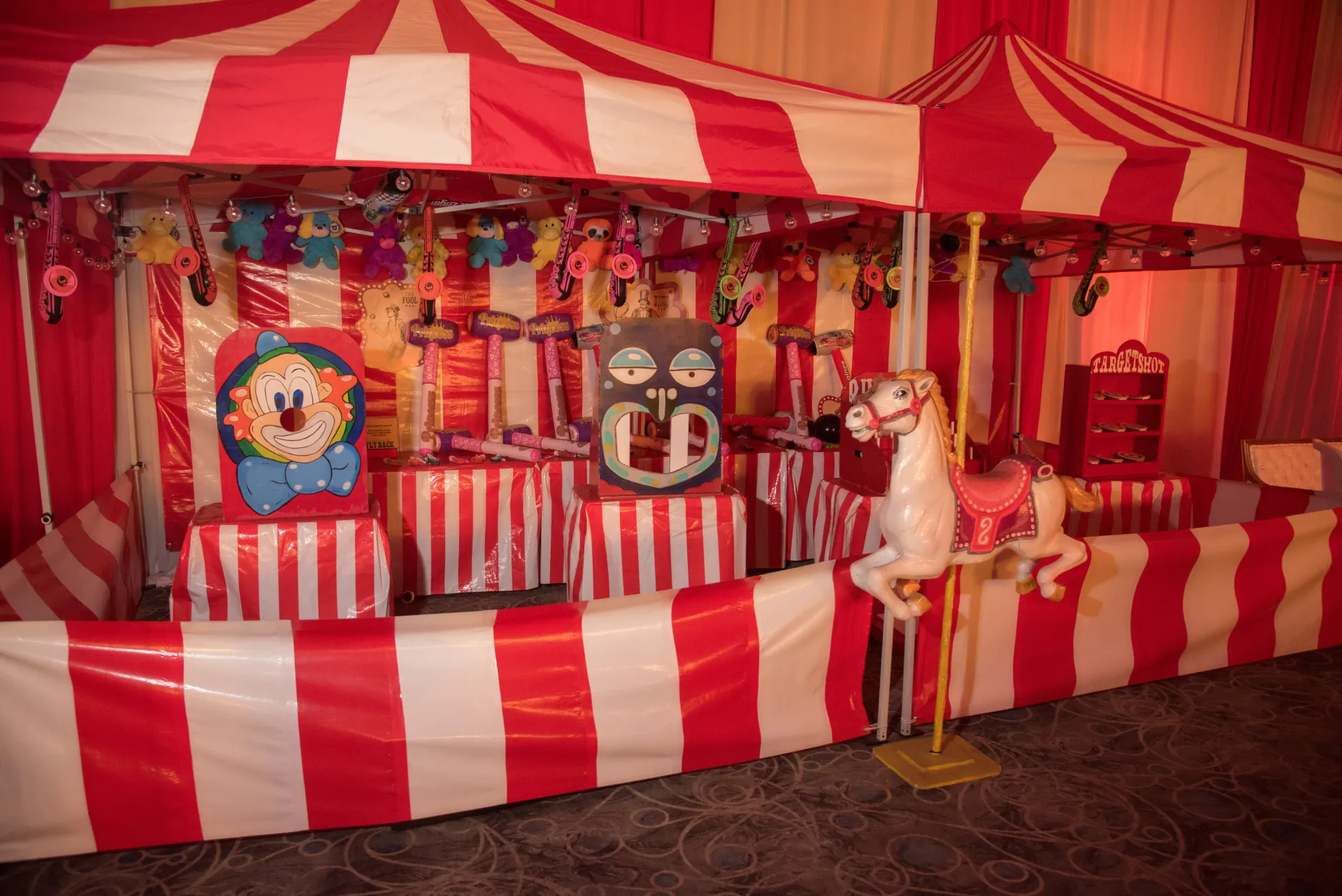 A striped 10x10 carnival concession booth with a popcorn machine and cotton candy spinner set up on a grass field