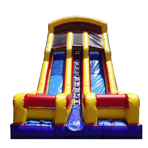 A combo inflatable with a slide set up on a paved lot near a recreation center, with a blower running off to the side