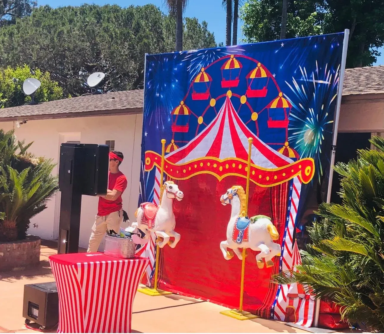 A backyard birthday party at a military housing home with a red-and-white striped carnival booth and a popcorn machine set up on the patio in Camp Pendleton, CA