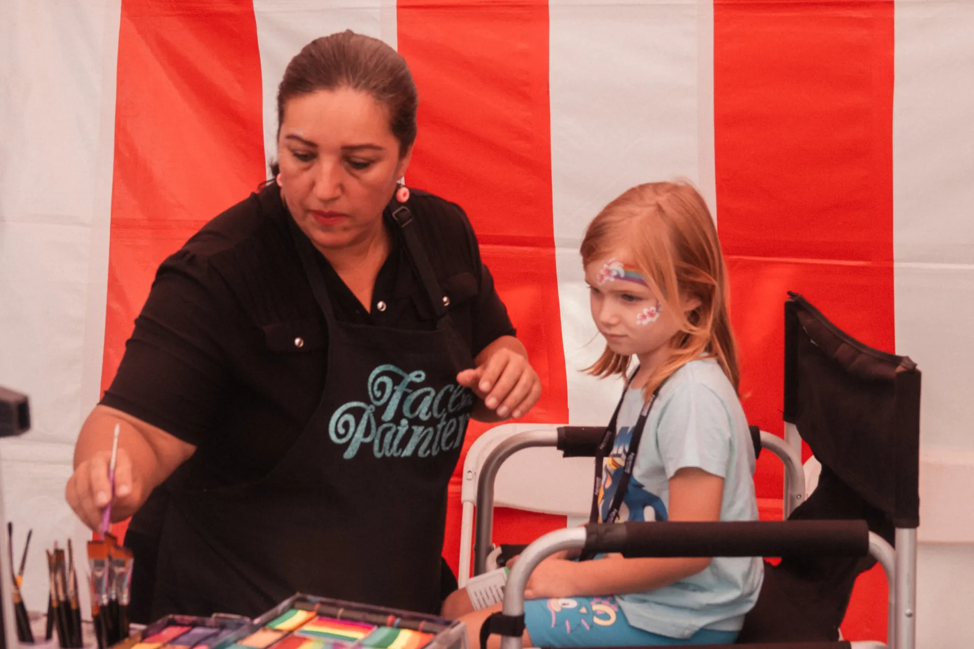 A small carnival game booth and prize table set up on a lawn near military family housing with a few kids playing