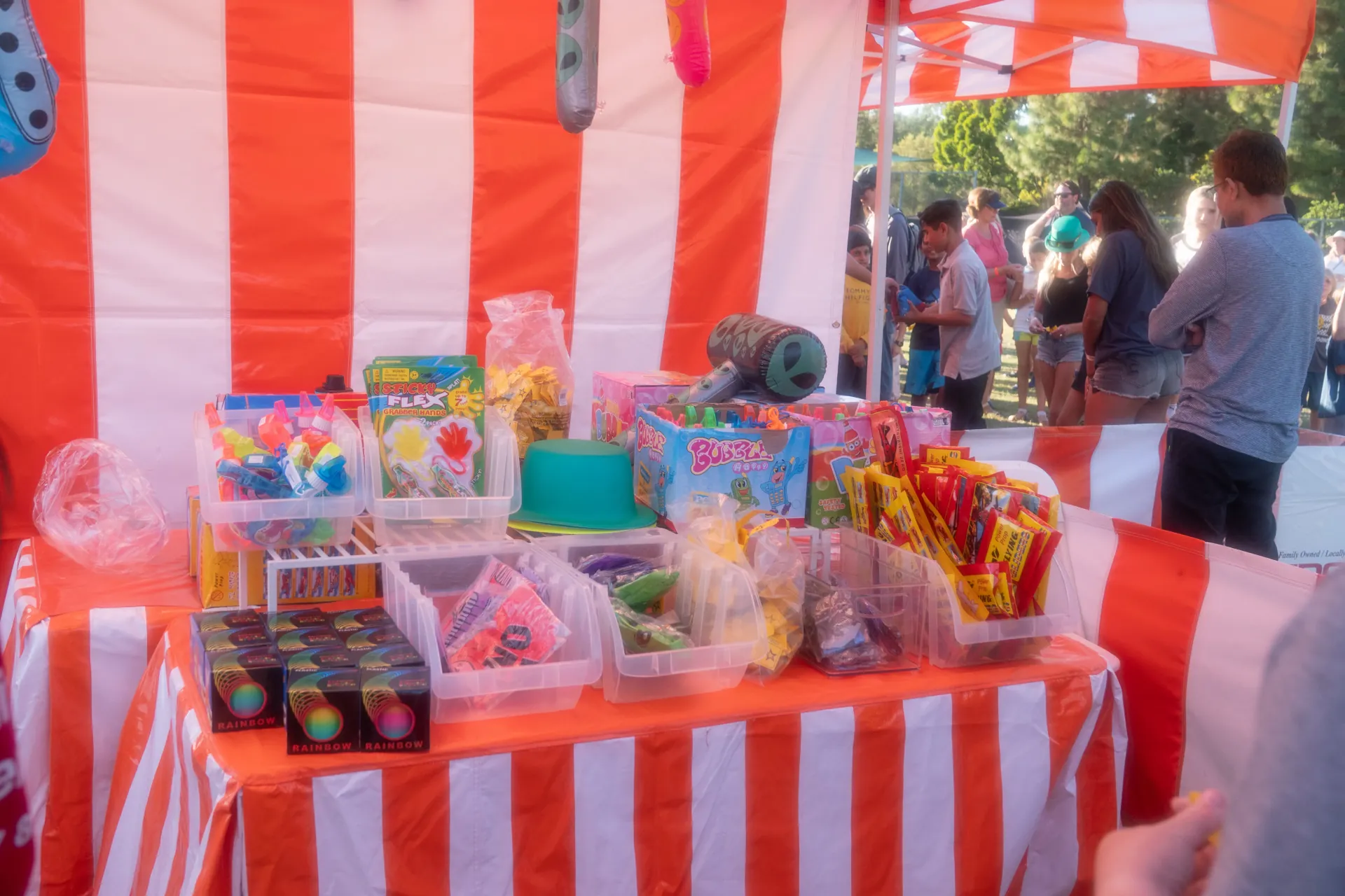 A concession table with a popcorn machine and cotton candy spinner set up under a canopy at an outdoor church festival