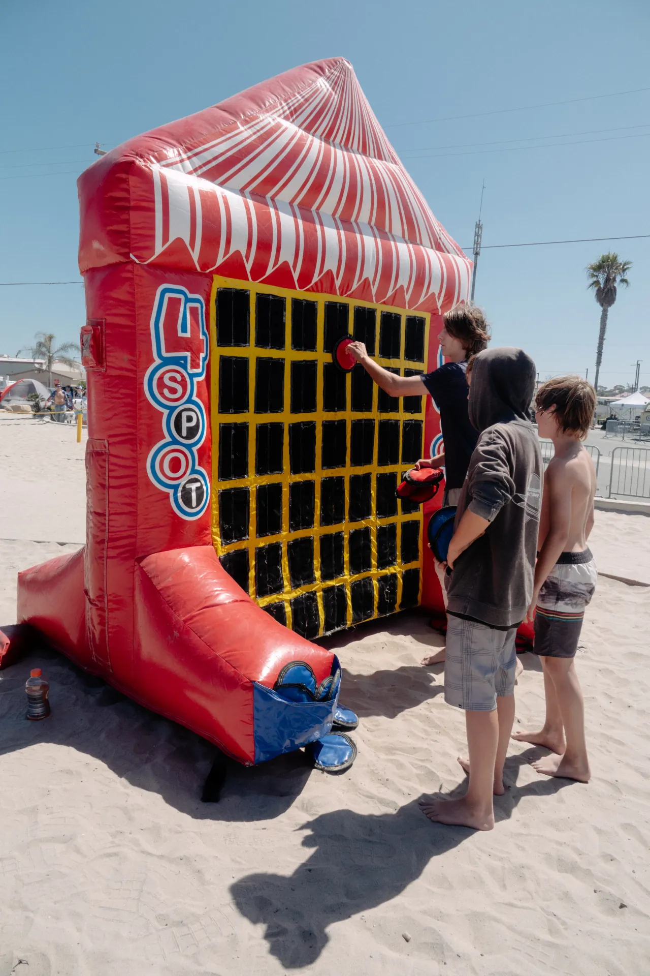 A generator and power distribution cart staged behind a row of carnival concession booths at an outdoor public park event