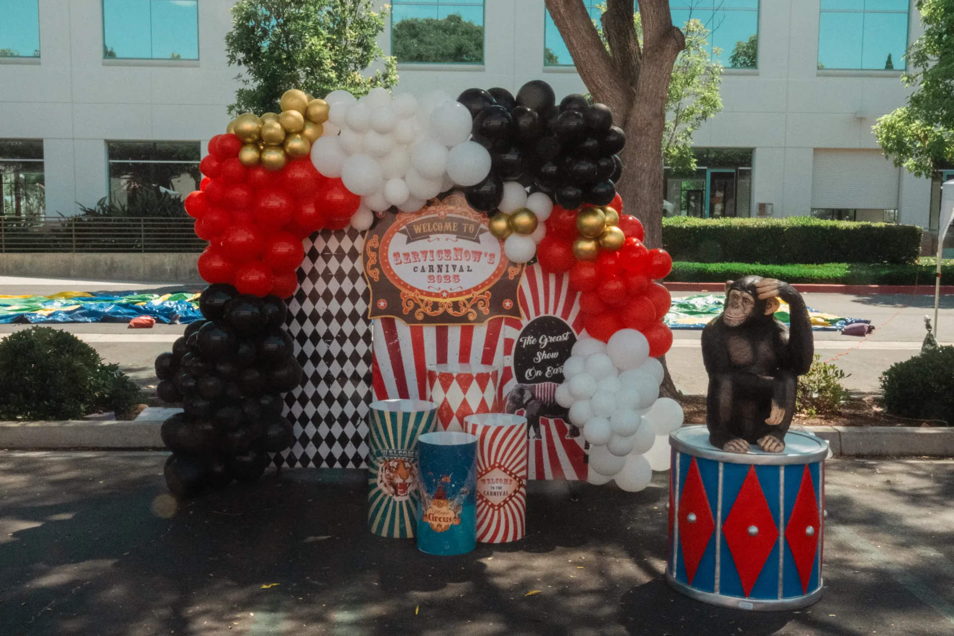 Rows of carnival game booths and a concession table set up on an open grass field at a company family day event