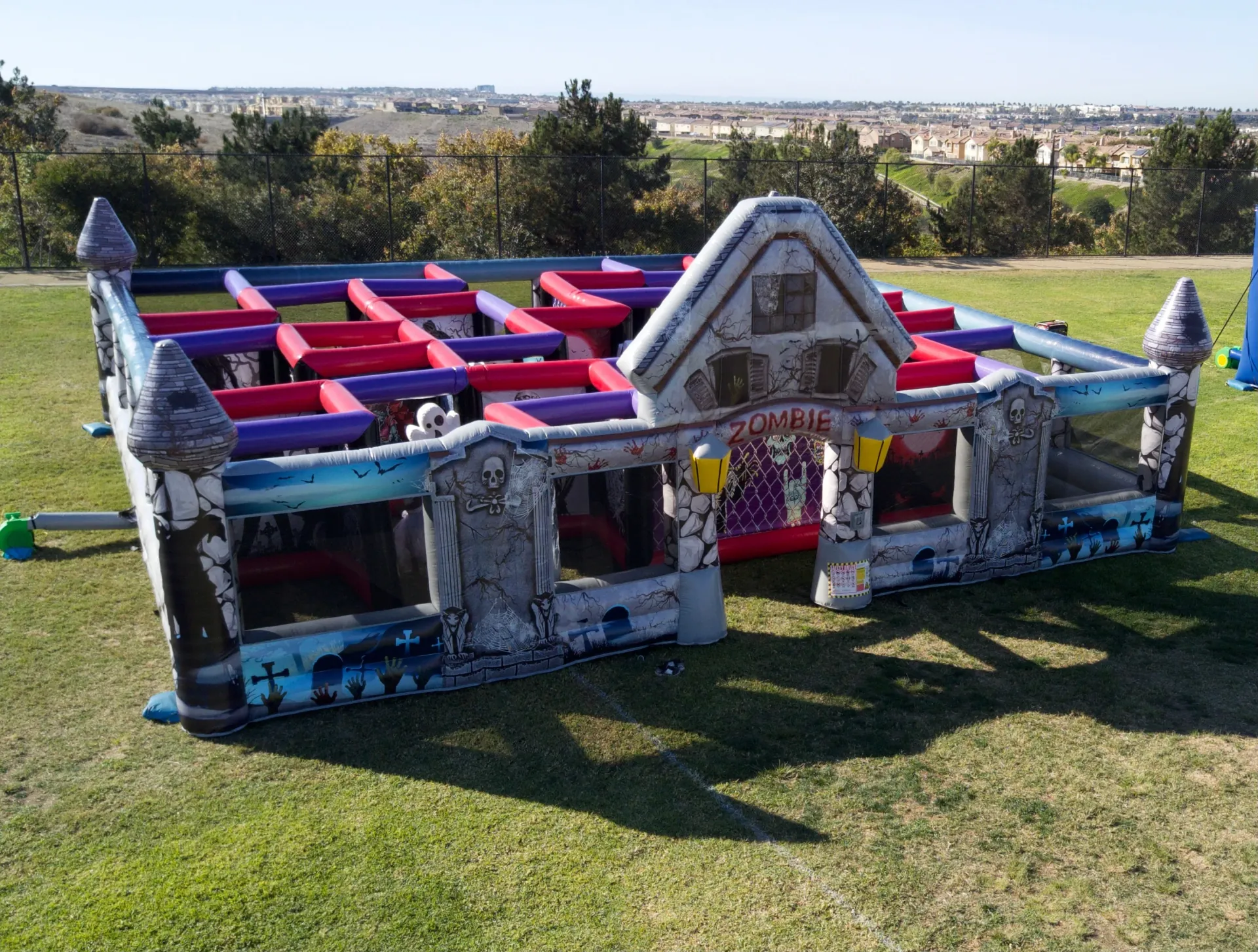 A holiday-themed carnival booth strung with string lights and garland, with a snow cones station and a Santa photo backdrop nearby in Camp Pendleton, CA